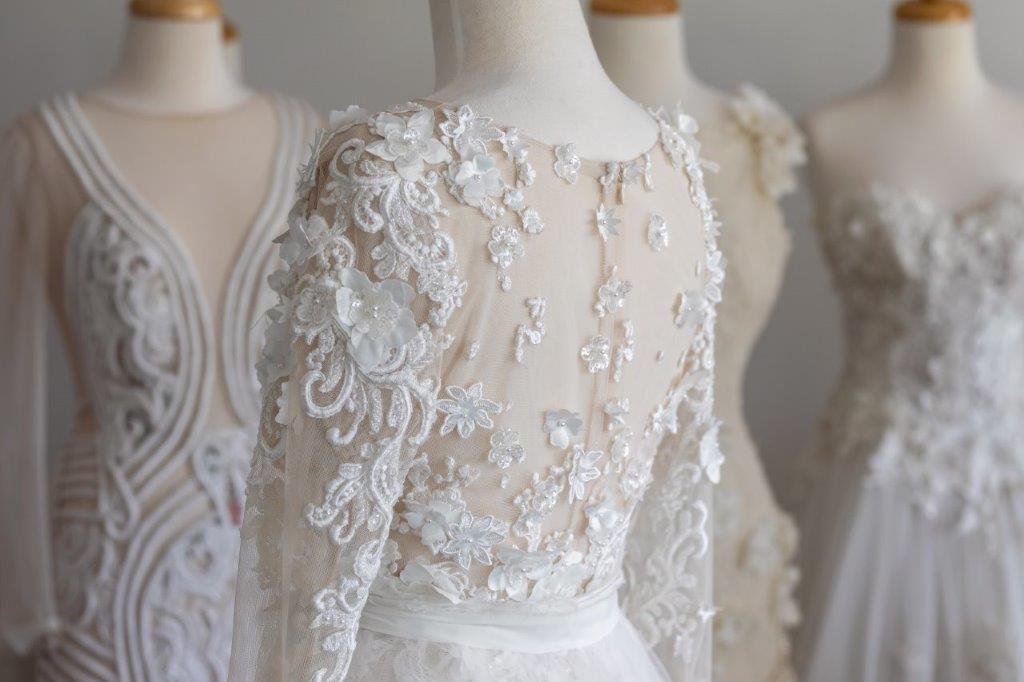 NOEMI: embroidered lace wedding gowns presented on stands, from the bridal gallery of La Maison de Couture